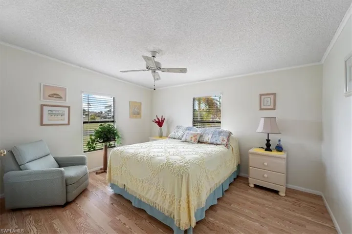 Bedroom with hardwood / wood-style flooring, crown molding, a textured ceiling, and multiple windows
