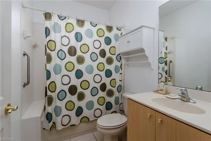 Bathroom featuring a single vanity, a built-in medicine cabinet, and a tiled shower with grab bar