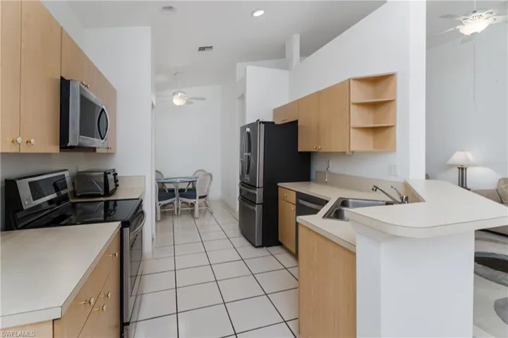 Kitchen featuring light wood-finish cabinetry, light-toned countertops, tile flooring, and a stainless steel appliance package