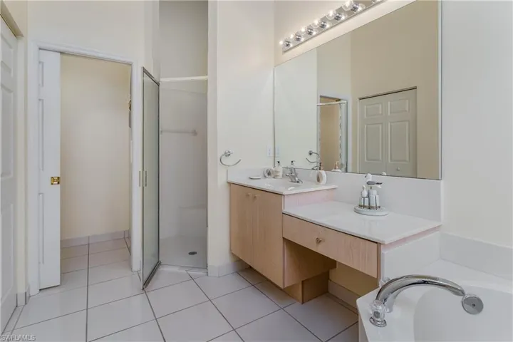 Built-in makeup vanity, large wall mirror, and walk-in shower with glass enclosure