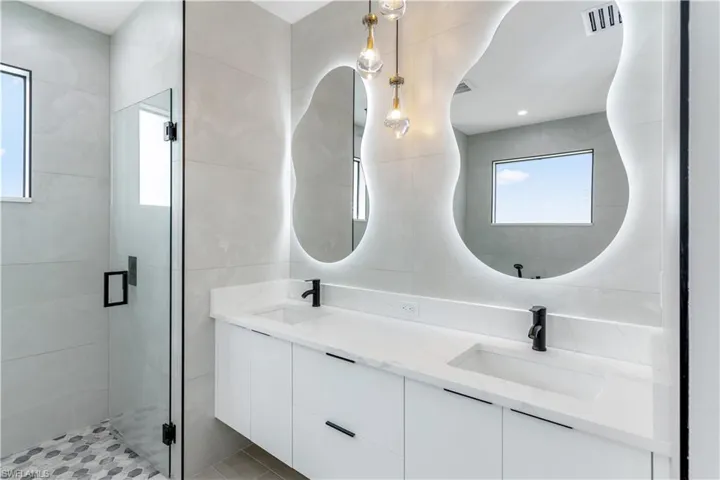 Bathroom with double vanity, a shower stall, and tile walls
