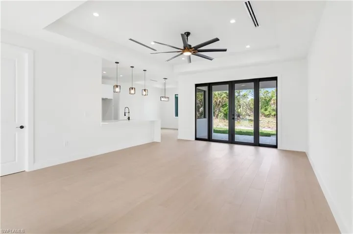 Unfurnished living room featuring a tray ceiling, ceiling fan, wood-look tile, french doors, and recessed lighting