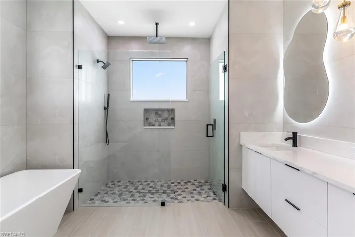Full bathroom with tile walls, a stall shower, and a soaking tub