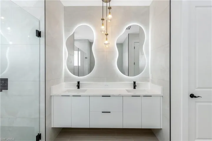 Full bath featuring tile walls, double vanity, and an enclosed shower