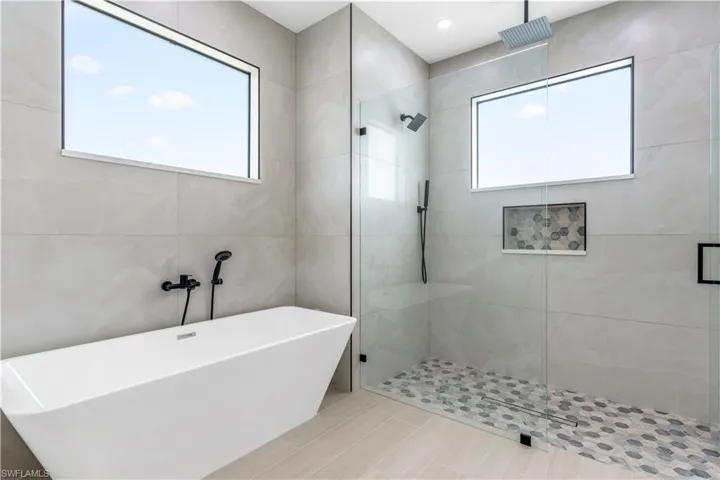 Full bath with a shower stall, a freestanding tub, and tile walls