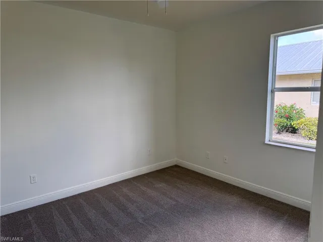 Empty room featuring baseboards and dark colored carpet