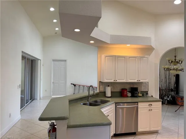 Kitchen with recessed lighting, a towering ceiling, dishwasher, a sink, and light tile patterned flooring