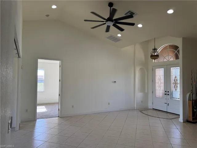 Entrance foyer with high vaulted ceiling, arched walkways, a ceiling fan, light tile patterned flooring, and baseboards