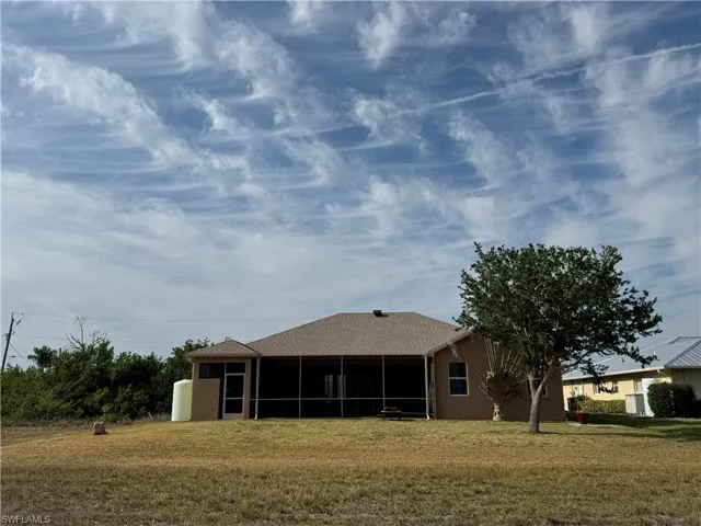 Back of property with a sunroom, a yard, and stucco siding