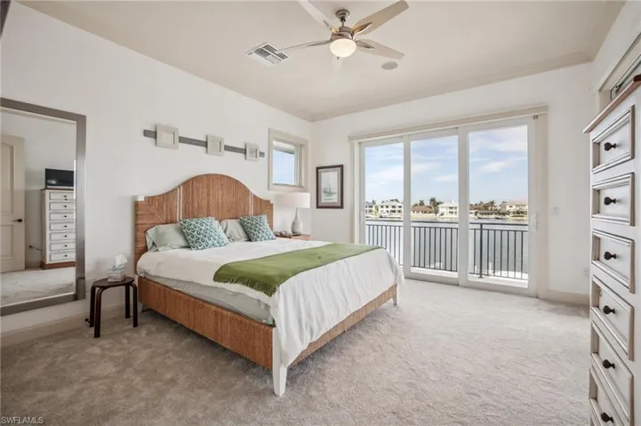 Bedroom featuring light colored carpet, access to outside, a water view, a ceiling fan, and ornamental molding