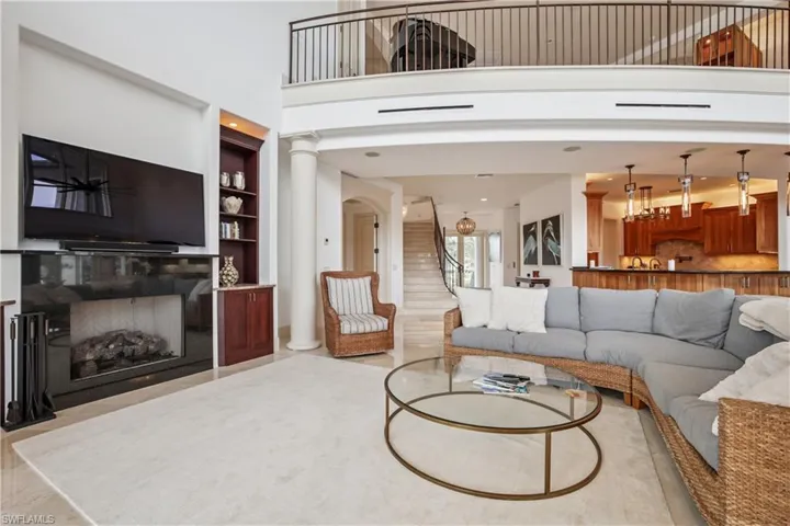 Living area with a high ceiling, a fireplace, stairway, built in features, and ornate columns