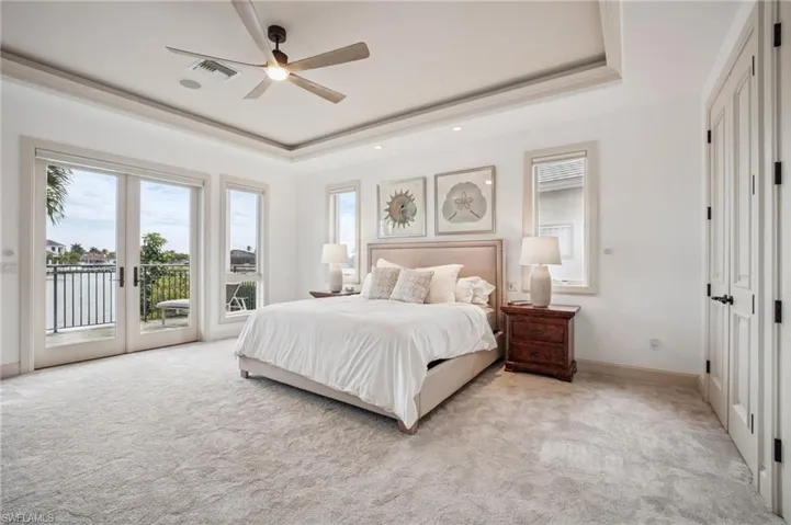 Bedroom featuring light carpet, a raised ceiling, access to outside, and ceiling fan