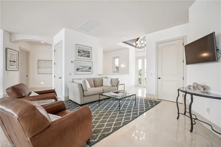 Living area featuring light tile patterned flooring, a chandelier, and arched walkways