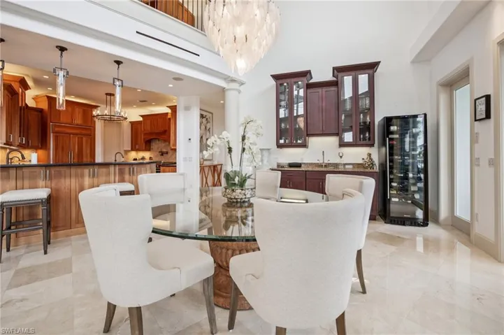 Dining area featuring beverage cooler, a chandelier, ornate columns, and a towering ceiling