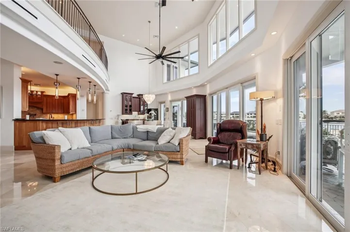 Living area with a ceiling fan, a towering ceiling, and recessed lighting