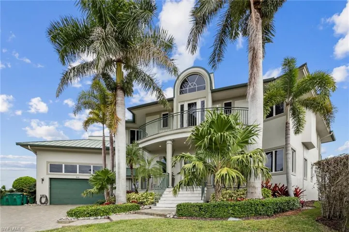 View of front facade with stucco siding, a balcony, a garage, decorative driveway, and a front lawn