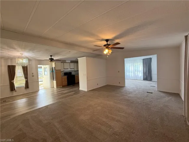 Unfurnished living room featuring carpet flooring, healthy amount of natural light, a ceiling fan, and beam ceiling