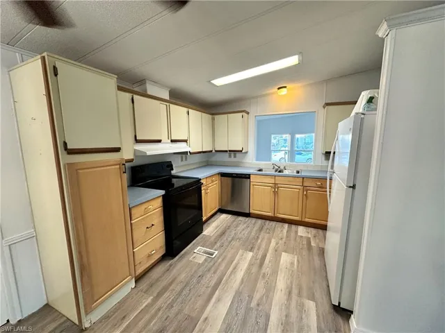 Kitchen featuring black electric range oven, freestanding refrigerator, light wood-style floors, dishwasher, and under cabinet range hood