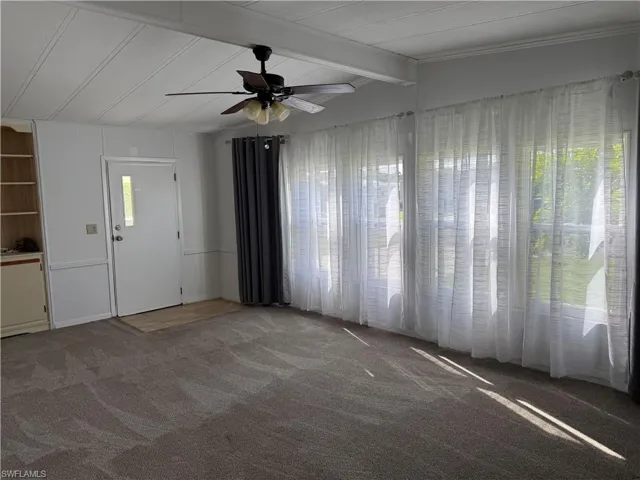 Unfurnished living room featuring carpet flooring and ceiling fan