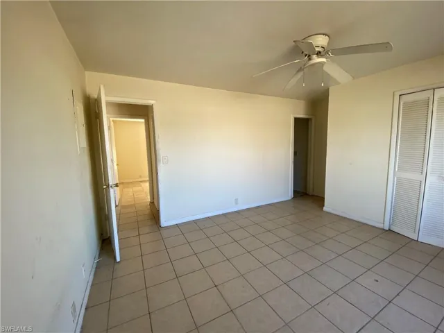 Unfurnished bedroom with a closet, a ceiling fan, and light tile patterned floors