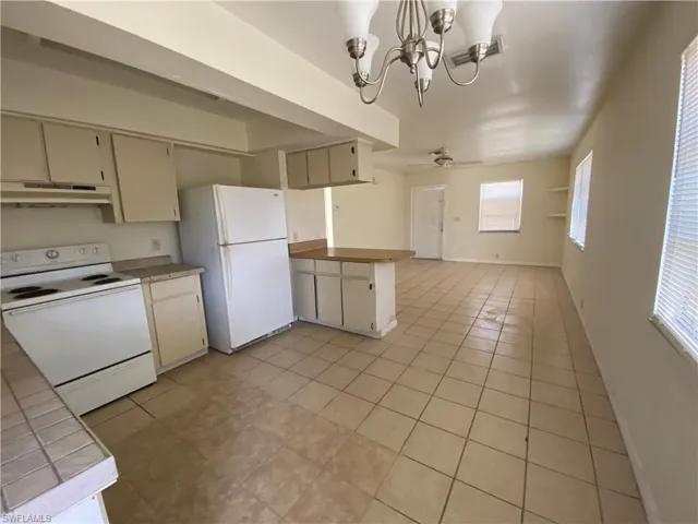 Kitchen featuring white appliances, a chandelier, open floor plan, light tile patterned floors, and a ceiling fan