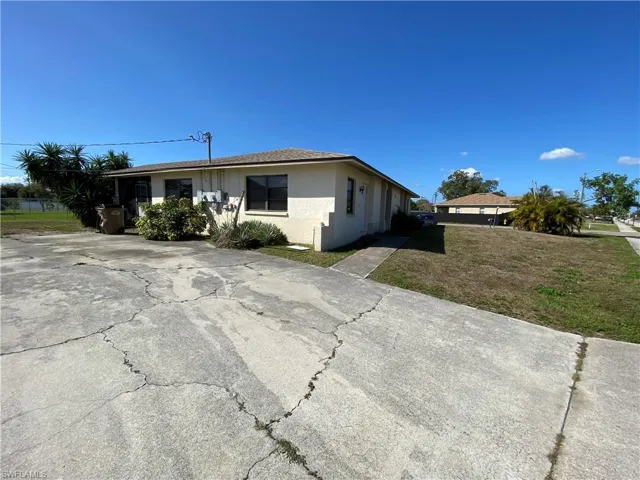 View of side of property featuring a lawn, stucco siding, and driveway