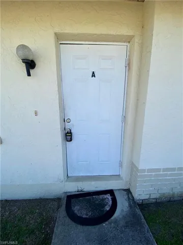 View of exterior entry with a lawn and stucco siding