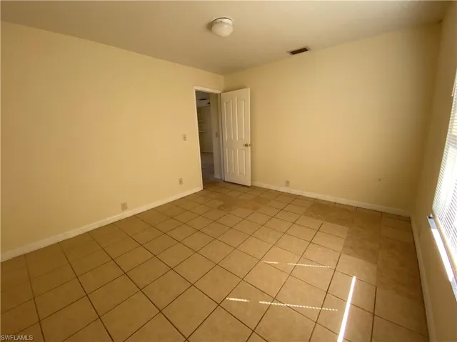 Empty room featuring light tile patterned floors and baseboards