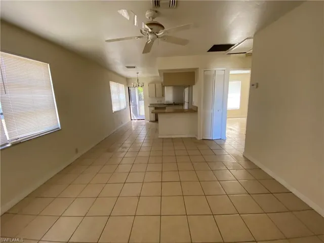 Unfurnished living room featuring ceiling fan, light tile patterned flooring, plenty of natural light, and hanging lights