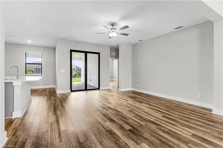 Empty room with beam ceiling, ceiling fan, dark wood-style floors, and recessed lighting