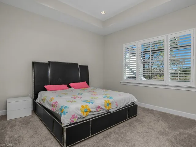 Master bedroom with a raised ceiling and recessed lighting, Plantation Shutters.