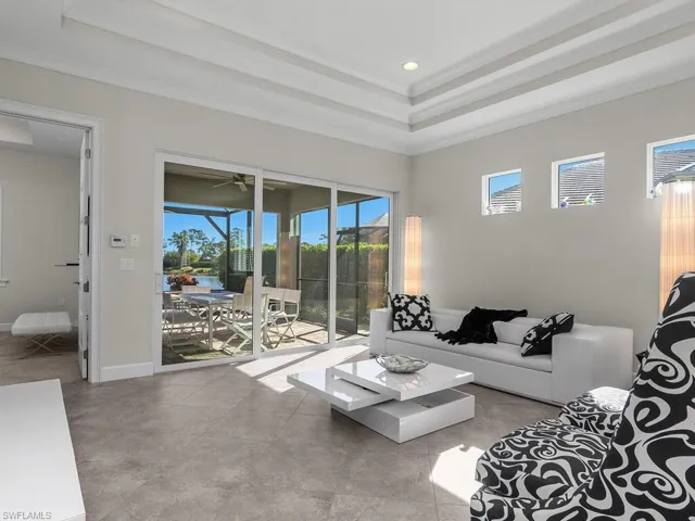 Living room leads to the lanai and pool area, a raised ceiling, recessed lighting, and ornamental molding.