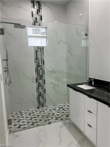Bathroom with vanity, tile patterned flooring, and a tile shower