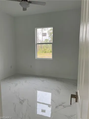 Empty room featuring tile patterned floors and ceiling fan