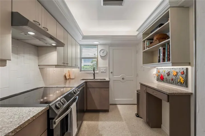 Kitchen featuring light stone counters, backsplash, ornamental molding, sink, and electric range