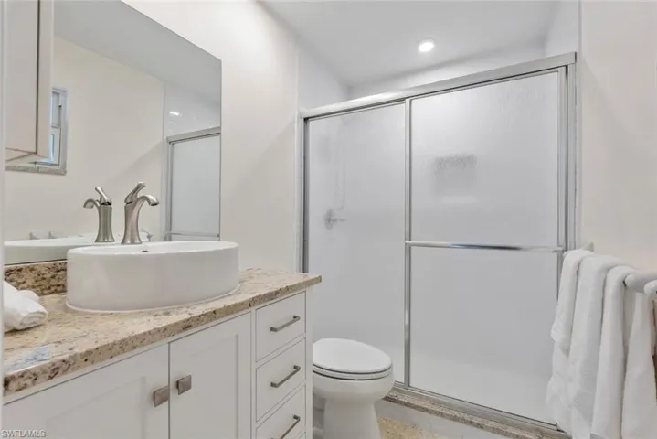 Bathroom featuring walk in shower, vanity, and toilet