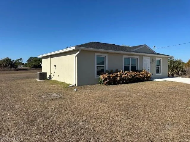 View of side of home featuring stucco siding and a yard
