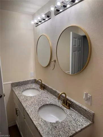 Full bath featuring double vanity and a textured wall