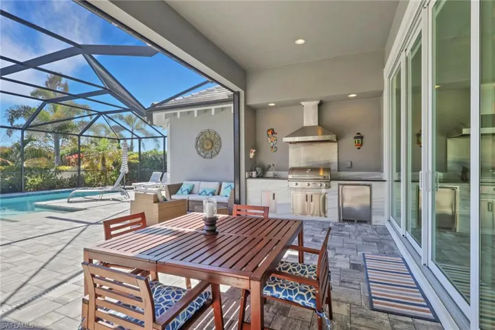 View of patio / terrace with an outdoor pool, area for grilling, a sunroom, a lanai, and an outdoor living / dining area