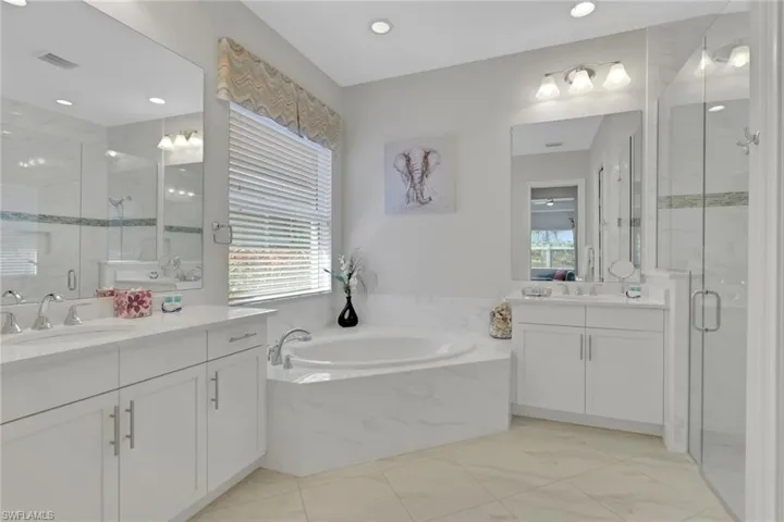 Full bath with a marble finish shower, a bath, and two vanities