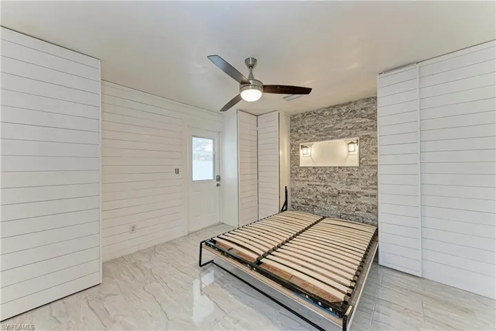Bedroom with ceiling fan and wood walls