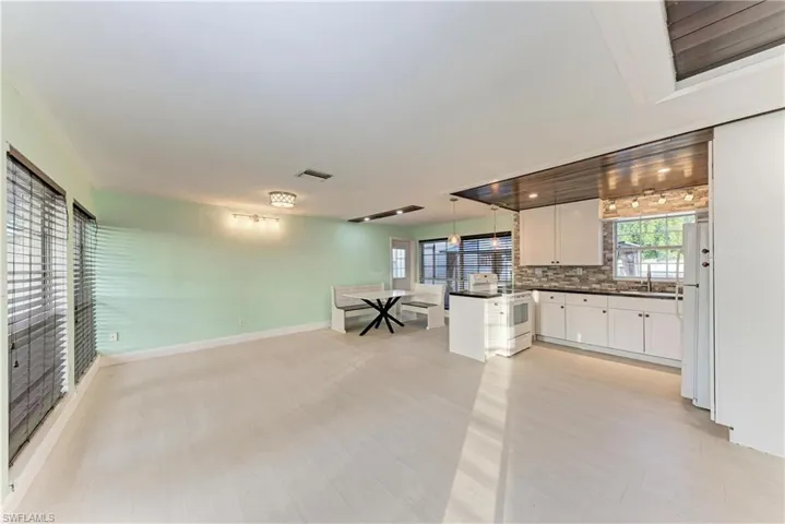 Kitchen featuring dark countertops, white cabinets, pendant lighting, open floor plan, and white appliances
