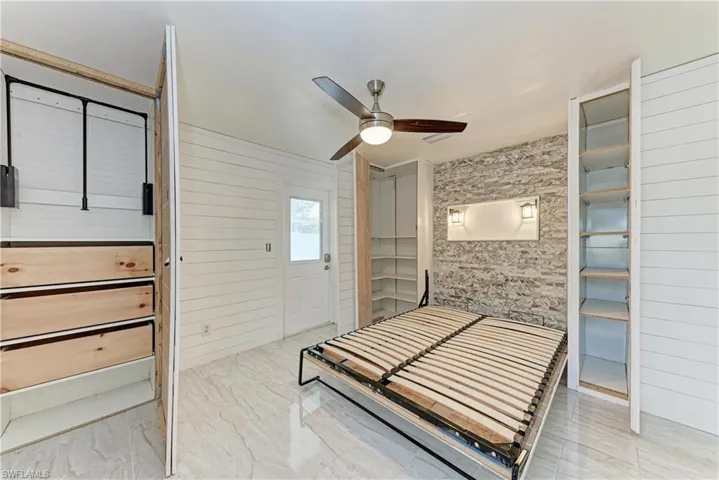 Bedroom featuring a ceiling fan and wood walls