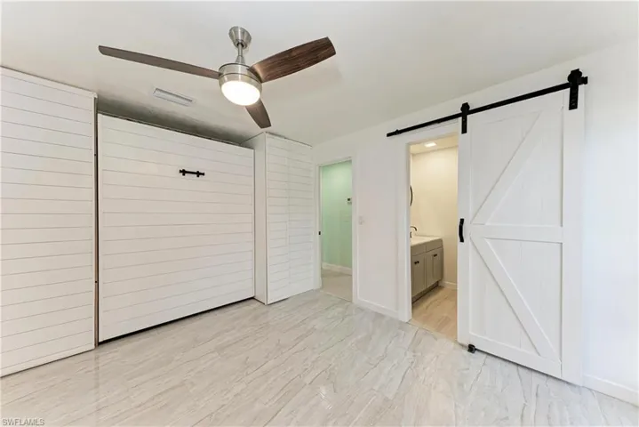 Unfurnished bedroom with a ceiling fan and connected bathroom