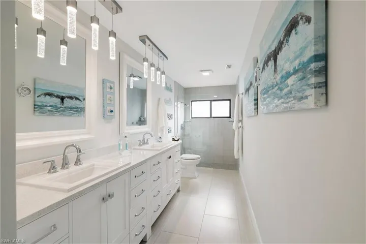 Bathroom with tile patterned flooring, vanity, tiled shower, and toilet