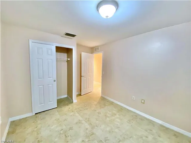 Room featuring neutral paint, tile flooring, flush-mount ceiling lighting, and a closet with sliding doors