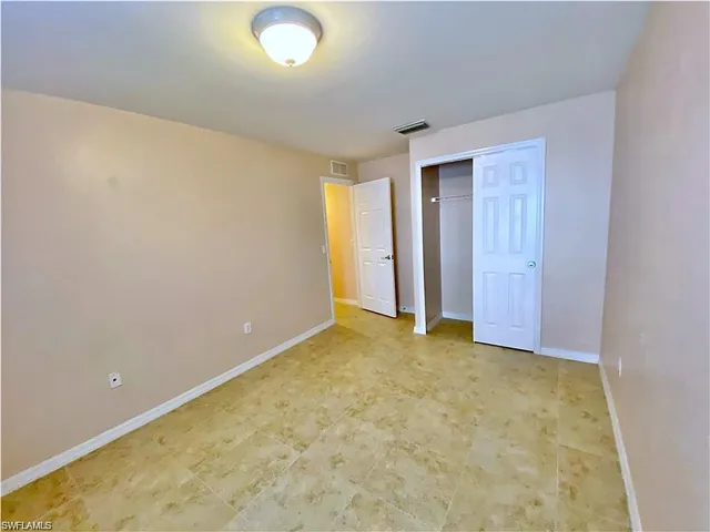 Interior room featuring large-format tile flooring, a closet with double-panel doors, neutral wall paint, and a ceiling-mounted flush-mount light fixture