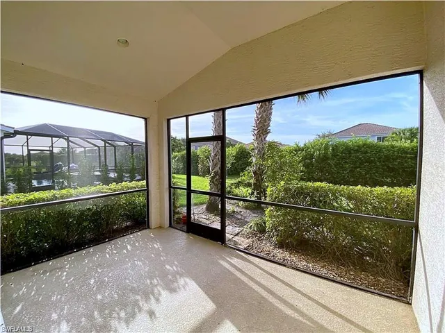 Screened-in lanai featuring a vaulted ceiling, concrete flooring, and metal frame enclosure with direct access to a landscaped backyard