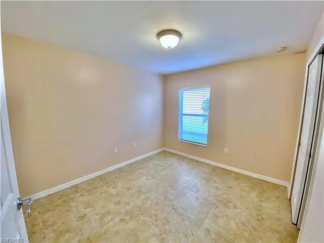 Neutral-toned interior space featuring light-colored tile flooring, a central flush-mount ceiling light fixture, and a window with horizontal blinds