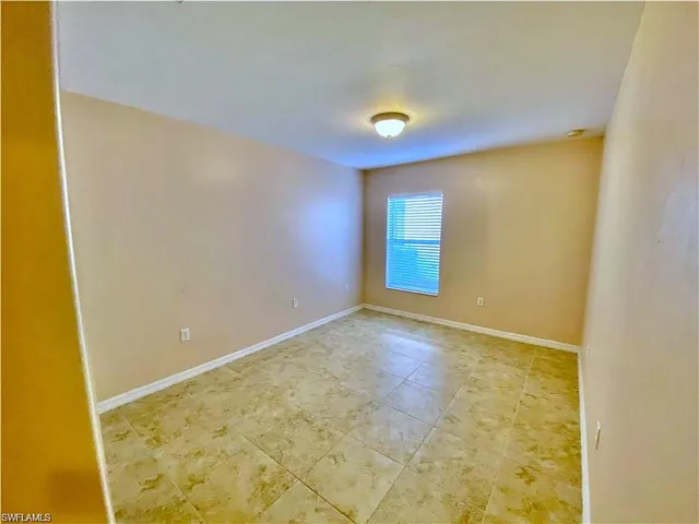 Neutral-toned interior space featuring light-colored tile flooring and a single-window design with horizontal blinds